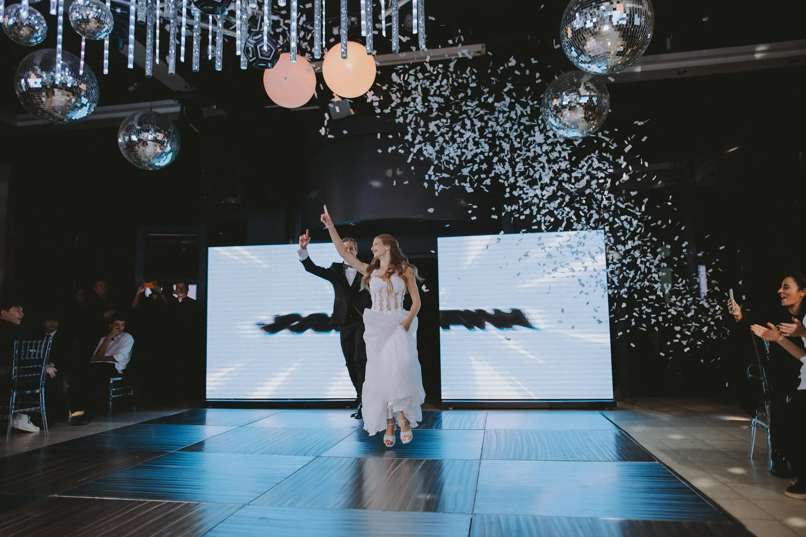 La entrada a la pista: la quinceañera llega de la mano entre papelitos, bolas de espejos y pantallas de luz.